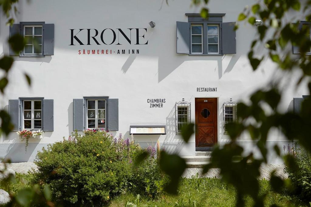 ein weißes Gebäude mit einer Tür und Fenstern in der Unterkunft Krone Säumerei am Inn in La Punt-Chamues-ch