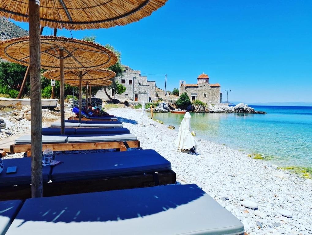 a woman walking on a beach with blue umbrellas at Ktima Zaxarias in Kokkala