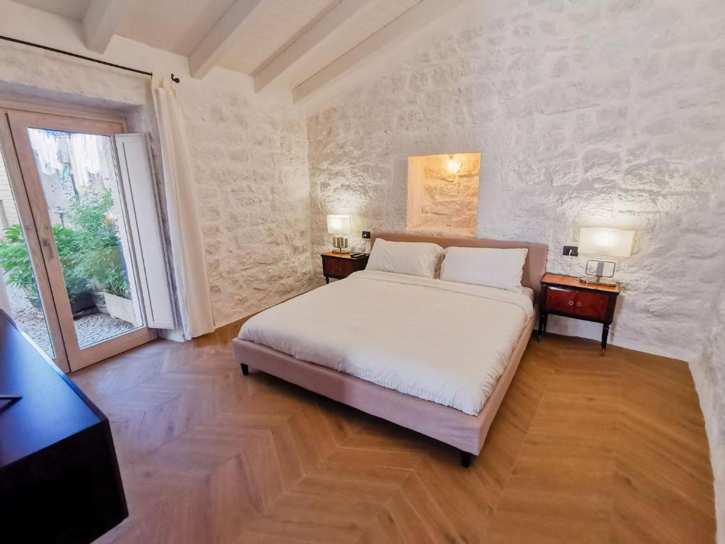 ein Schlafzimmer mit einem Bett, zwei Tischen und einem Fenster in der Unterkunft Affittacamere Faber in Tempio Pausania