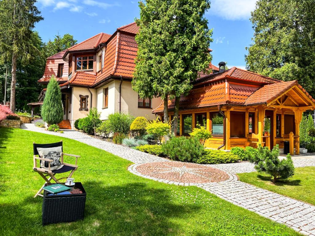 a house with a garden and a chair in the yard at Villa Filmowiec in Polanica-Zdrój