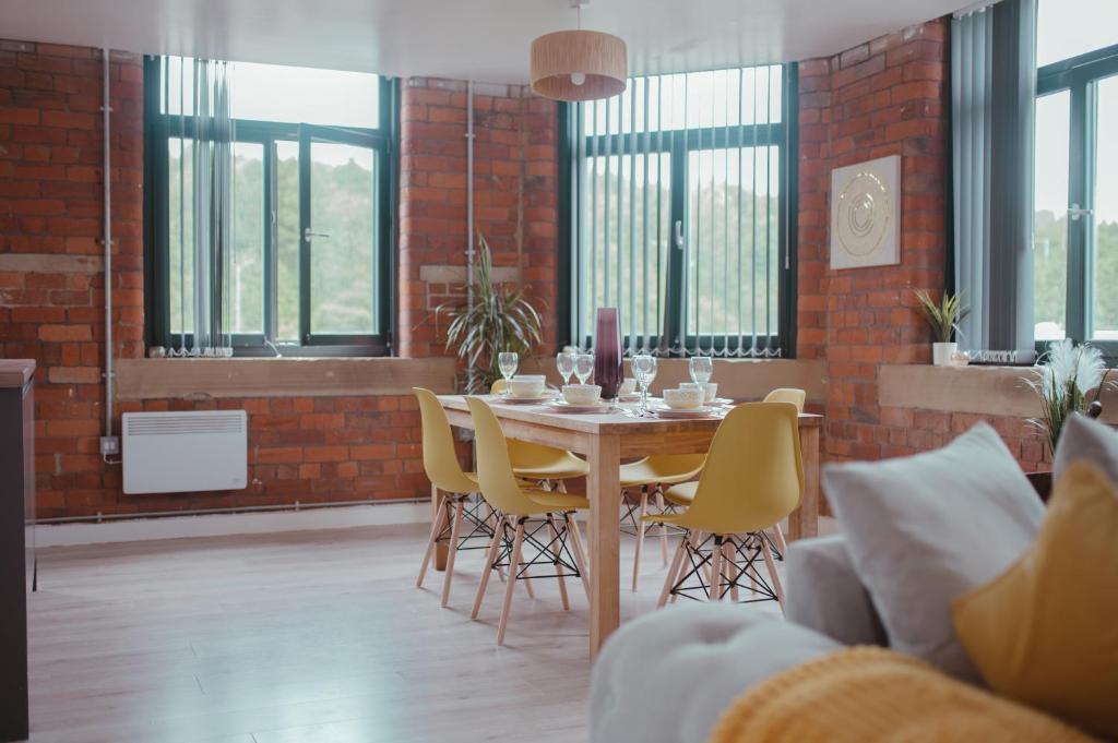 ein Esszimmer mit einem Tisch und gelben Stühlen in der Unterkunft Bv Luxury Apartment Penthouse Conditioning House in Bradford