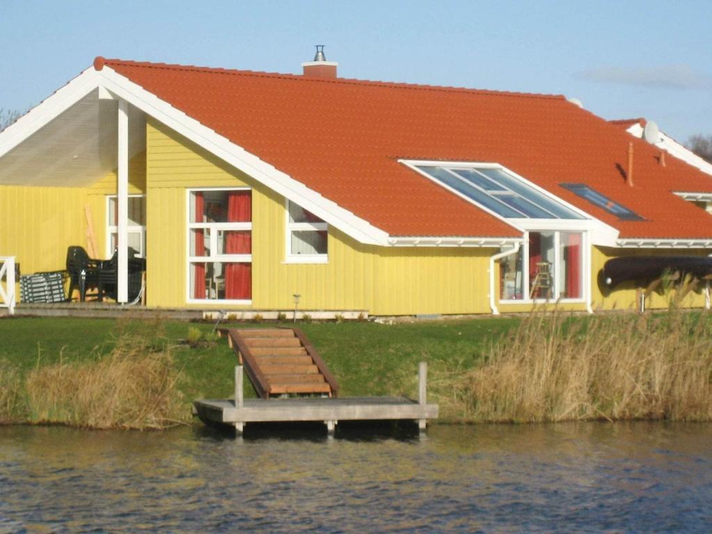 żółty dom z dokiem w wodzie w obiekcie 12 person holiday home in Otterndorf w mieście Otterndorf