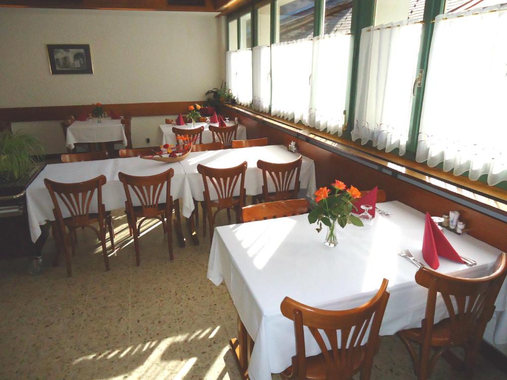 a dining room with white tables and chairs and windows at Hotel de l'Union in Orsières
