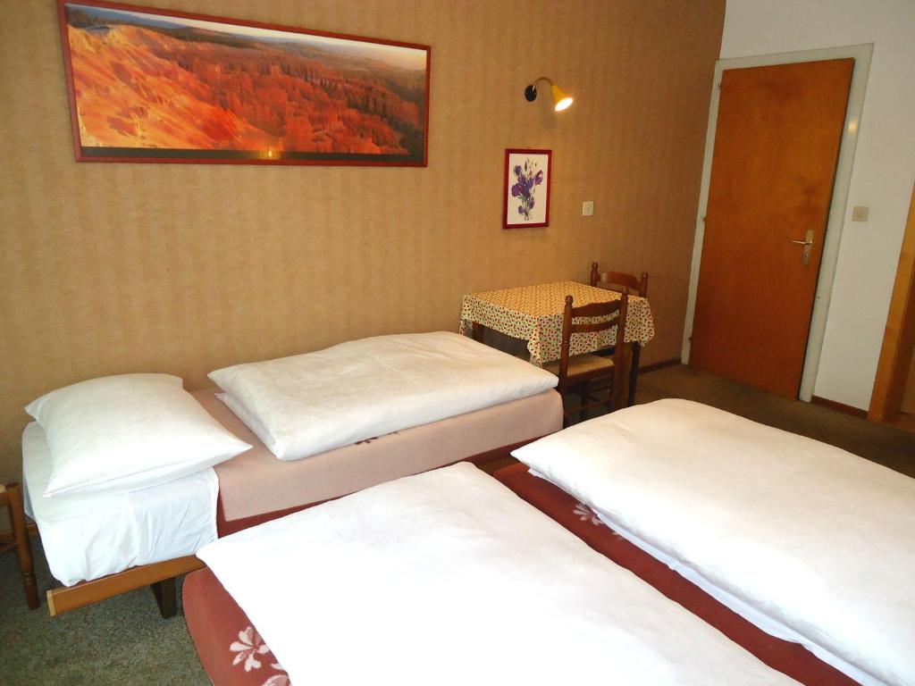 a room with three beds and a table and a painting at Hotel de l'Union in Orsières