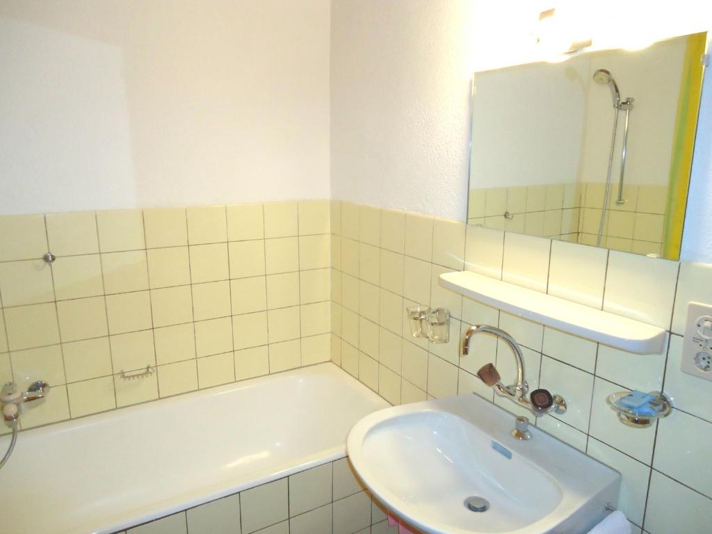 a bathroom with a sink and a tub and a mirror at Hotel de l'Union in Orsières