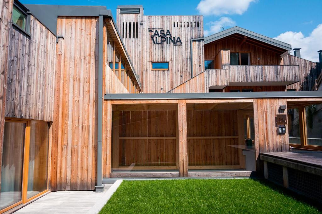 a house with a wooden facade with a garage at Residence Hotel Casa Alpina Serrada in Folgaria