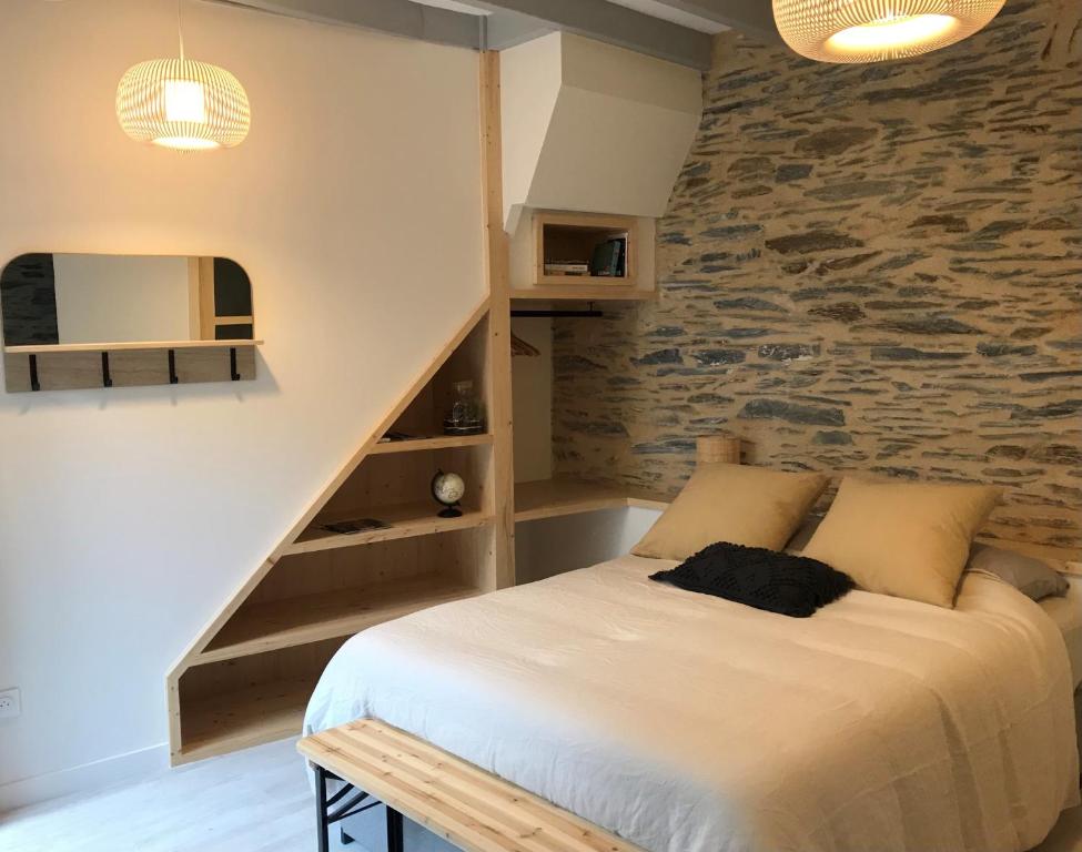 um quarto com uma cama e uma parede de pedra em La Maison du Cocher - Studio climatisé en Hypercentre em Angers