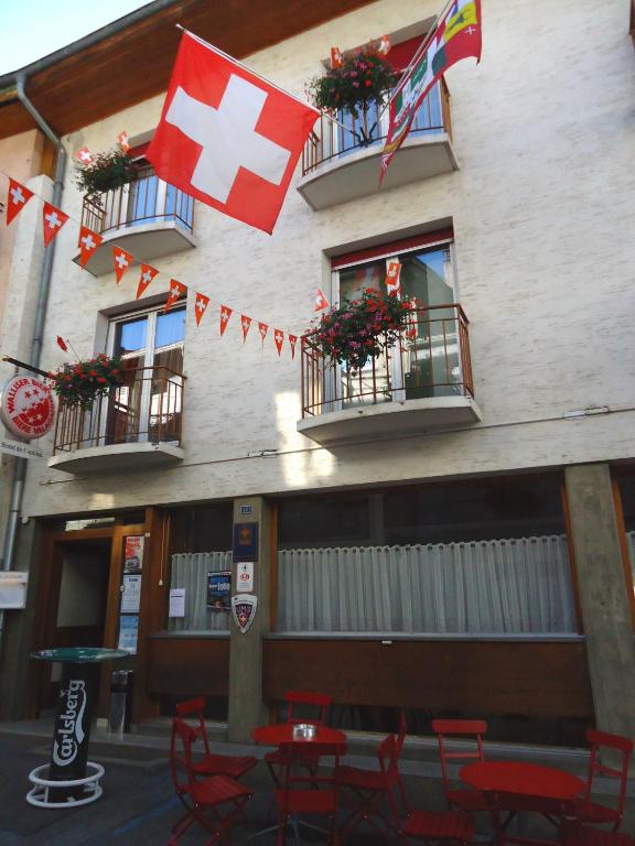a building with flags and tables and chairs in front of it at Hotel de l'Union in Orsières