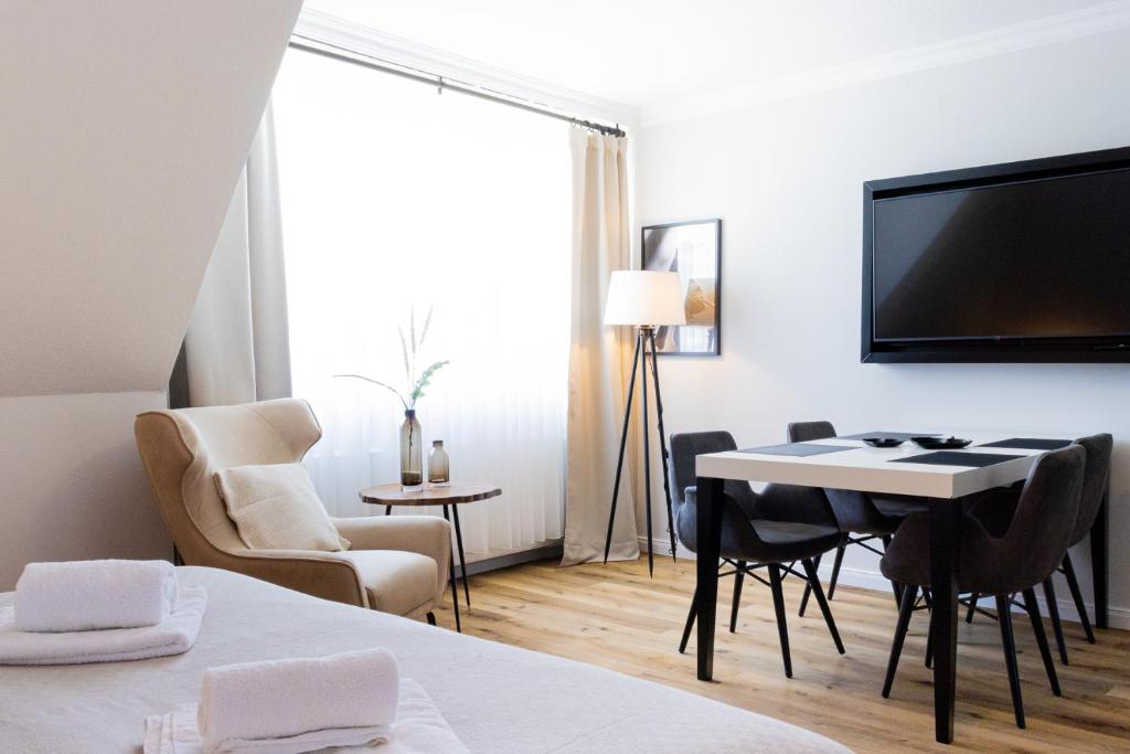 a room with a table and chairs and a tv at Strandnahe & hochwertige Ferienunterkunft, mit Gartenzugang, Parkplatz und Fahrradunterstellplatz in Scharbeutz
