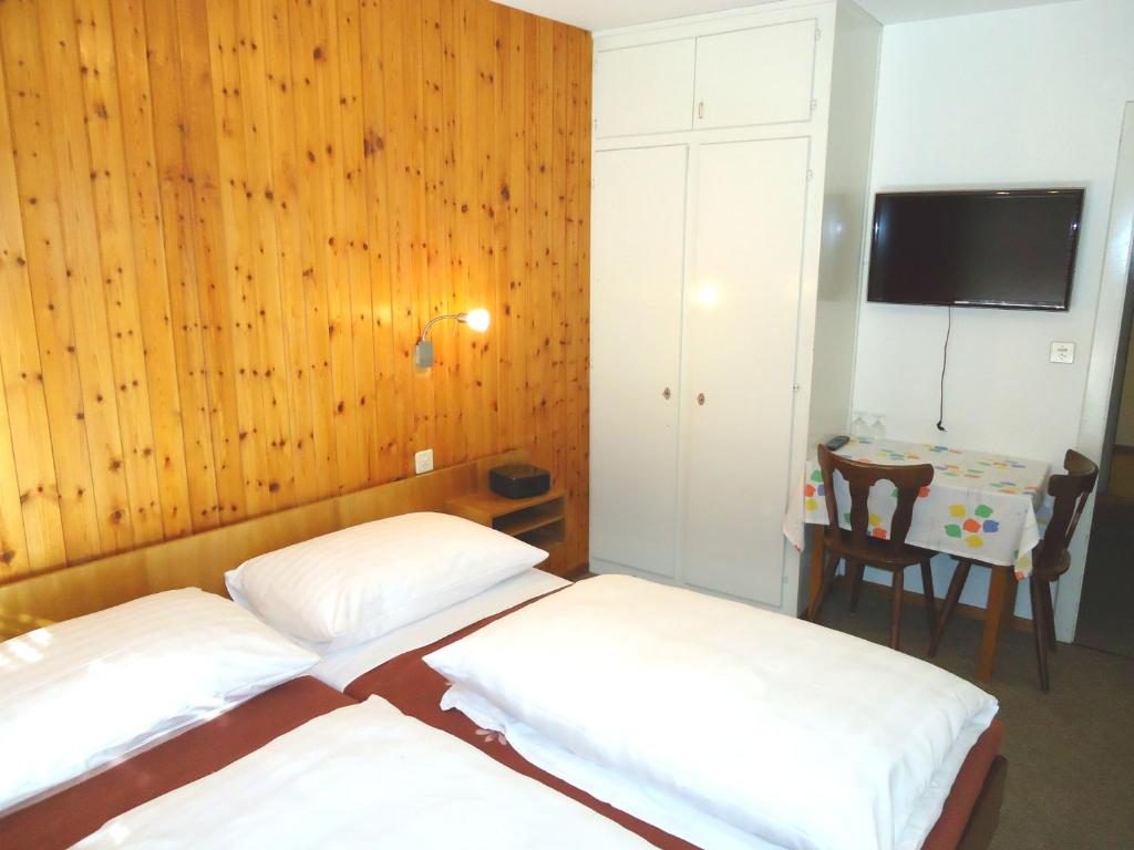two beds in a room with wooden walls and a table at Hotel de l'Union in Orsières