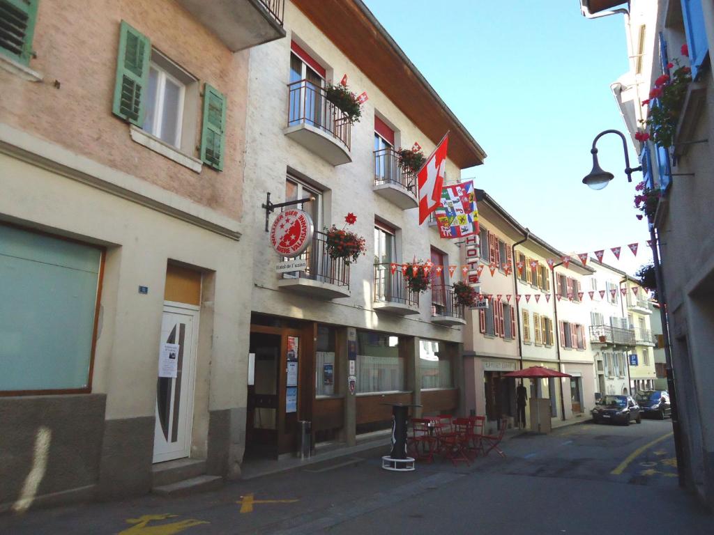 a building with flags and tables and chairs on a street at Hotel de l'Union in Orsières