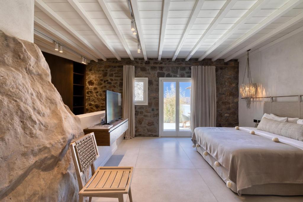 a bedroom with a bed and a television and a table at Mykonos Panormos Villas in Mykonos