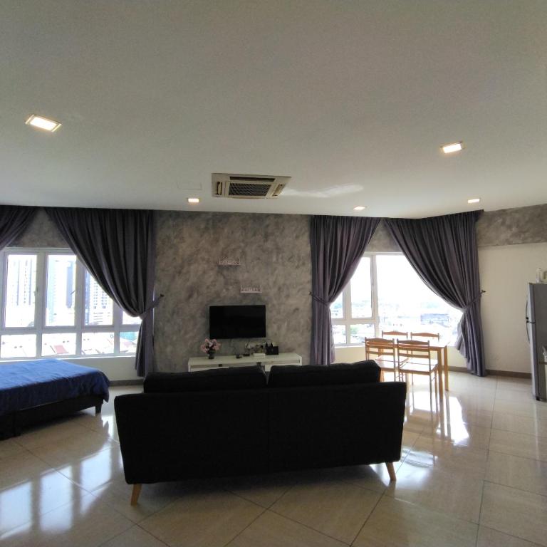 ein Wohnzimmer mit einem Sofa und einem TV in der Unterkunft Octagon Premium Ipoh Town Center 2BR 121 by Grab A Stay in Ipoh