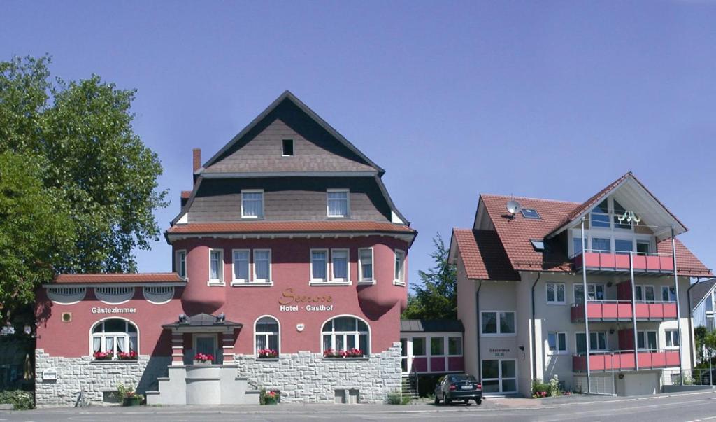 een groot rood gebouw naast twee gebouwen bij Gasthof Seerose in Radolfzell am Bodensee