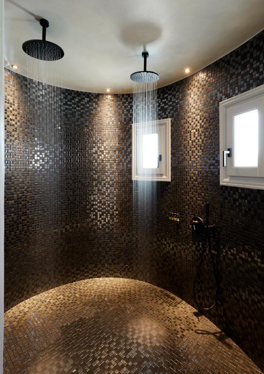 a bathroom with a shower with a large tub at Kalisti Hotel & Suites in Fira