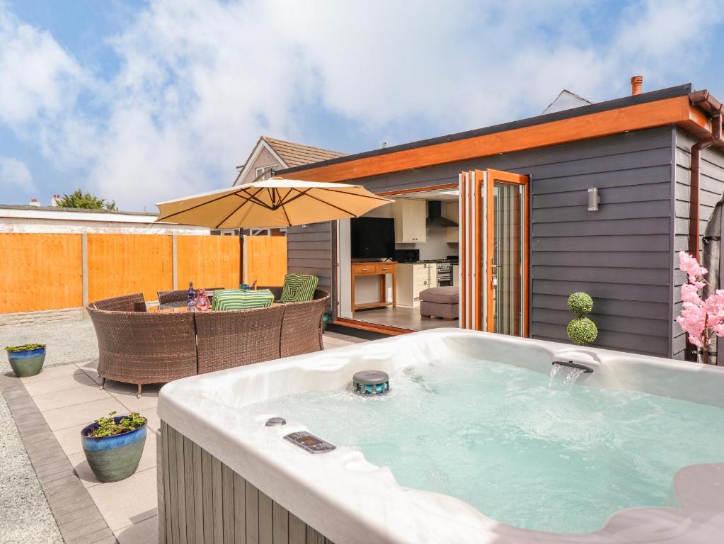 a hot tub sitting on a patio with an umbrella at Trefin in Cemaes Bay