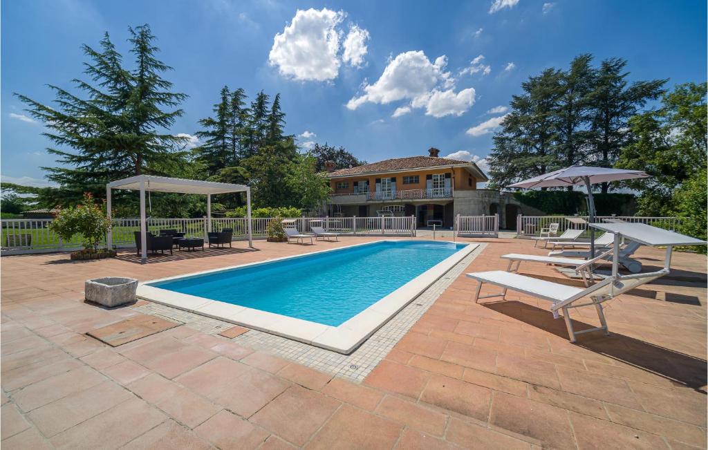 a swimming pool with chairs and umbrellas in front of a house at Nice Home In Asti With Jacuzzi in Asti