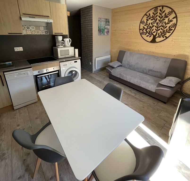 a kitchen and living room with a white table and chairs at Le Martin pêcheur, Appartement proche hyper centre in Le Mont-Dore