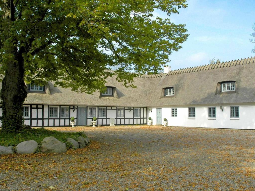 un gran edificio blanco con un árbol delante en 18 person holiday home in N rre Aaby en Føns