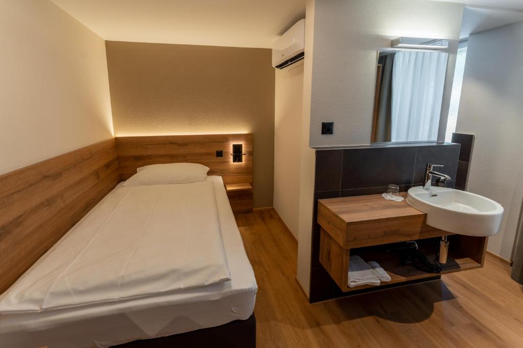 ein kleines Schlafzimmer mit einem Bett und einem Waschbecken in der Unterkunft ZIEGELHÜSI Hotel, Stettlen bei Bern in Bern