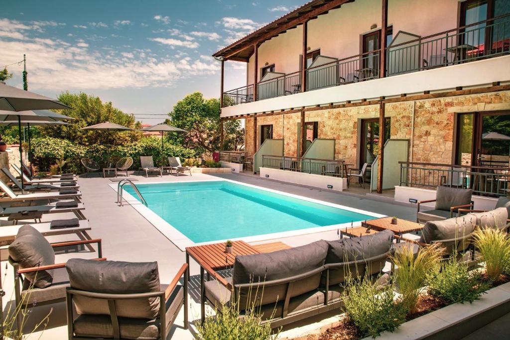 an outdoor swimming pool with chairs and a building at IADES suites in Afitos