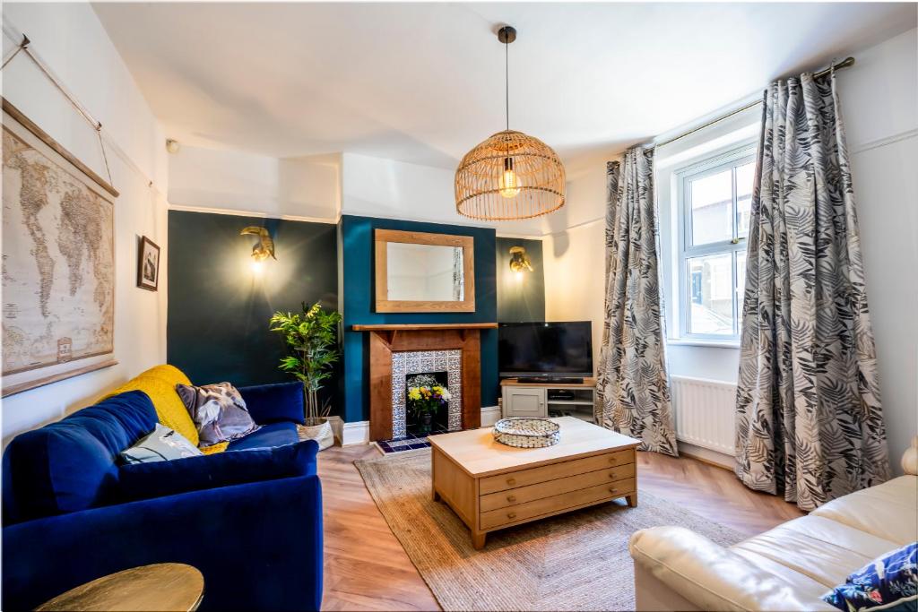 a living room with a blue couch and a fireplace at Shorethwaite in Amble