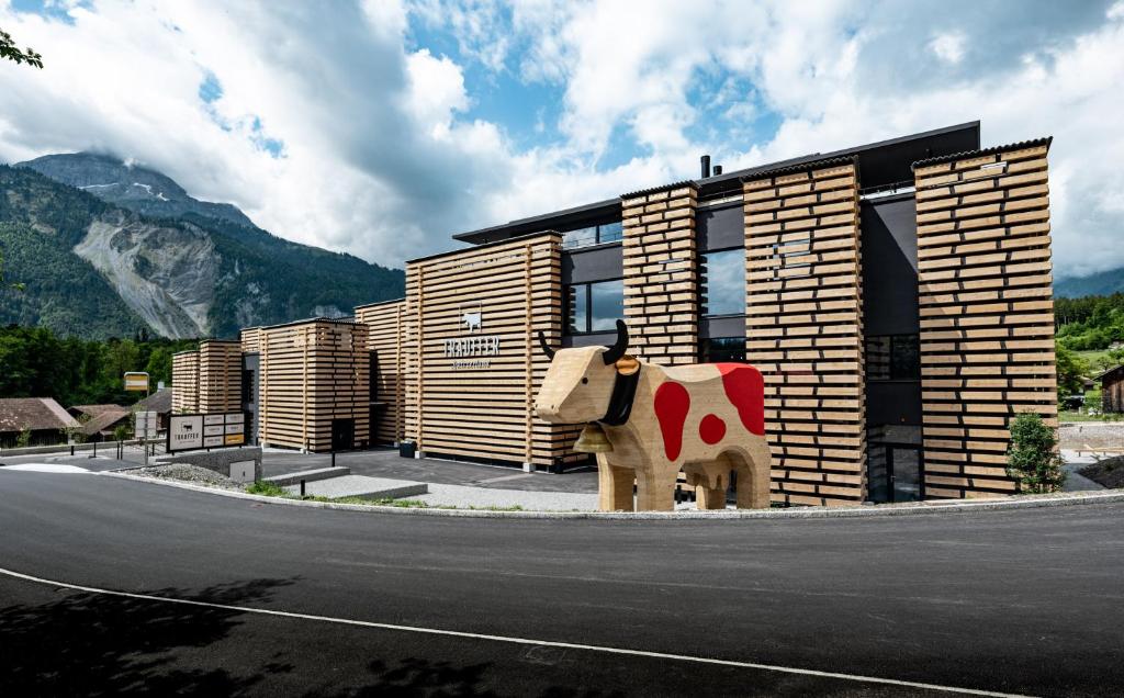 a building with a cow statue next to a street at Bretterhotel in Brienz