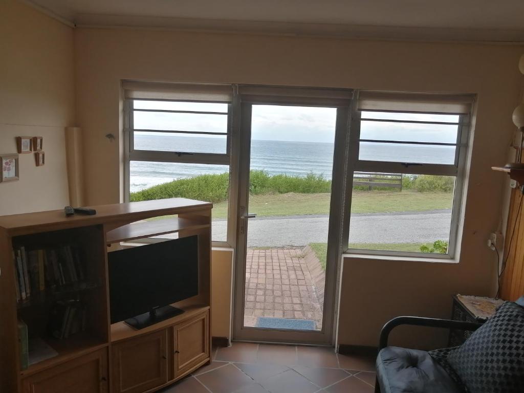 een woonkamer met een televisie en een glazen schuifdeur bij NOU TOE NOU in Tergniet