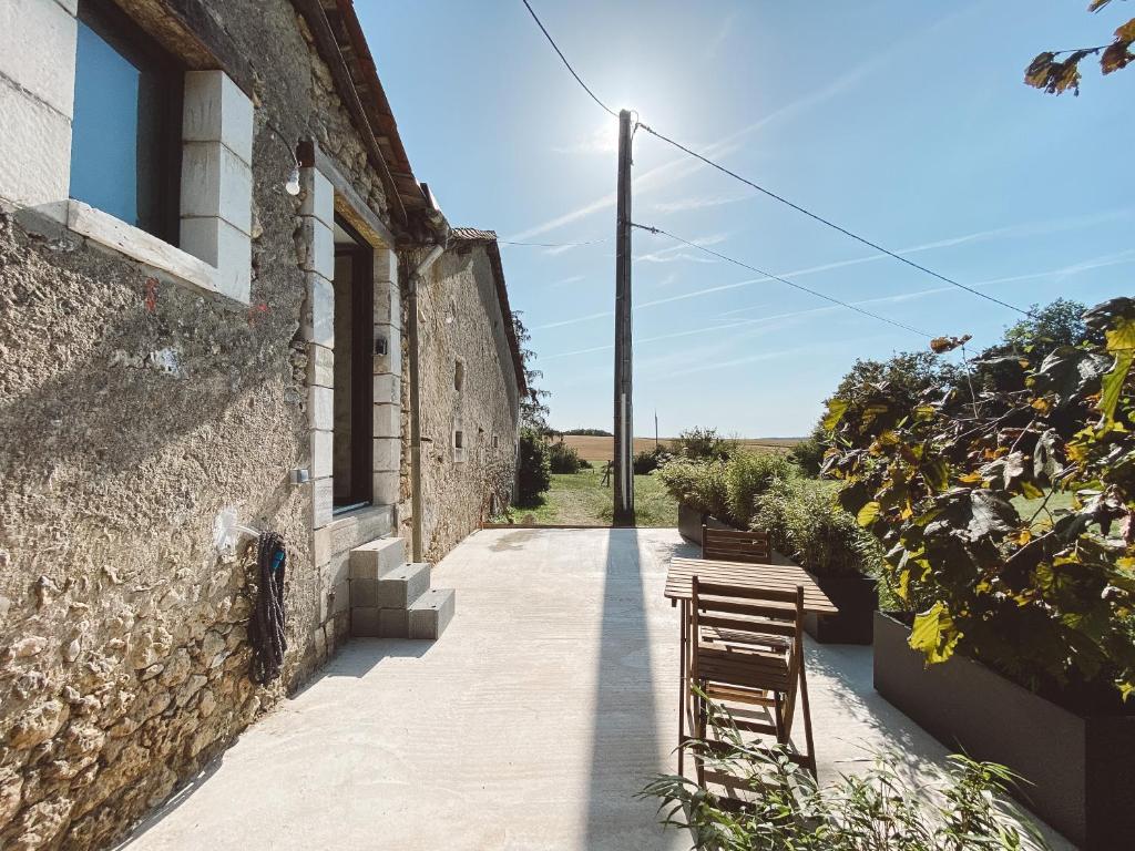 patio ze stołami i krzesłami obok budynku w obiekcie La Parenthèse, joli studio avec terrasse w mieście Valeuil