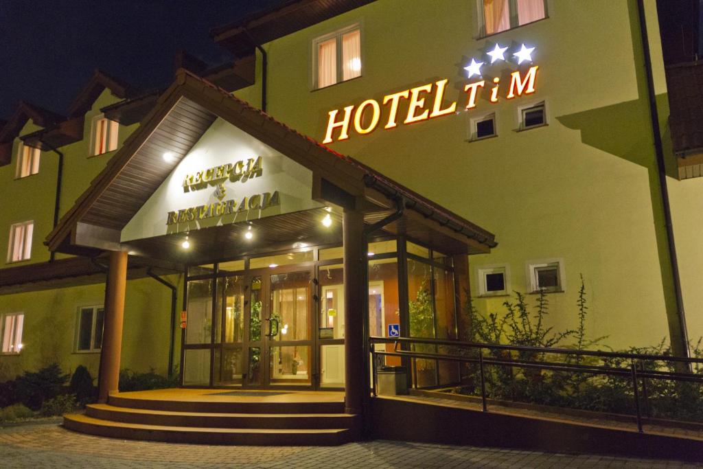 a hotel with a neon sign in front of it at Hotel TiM in Cekanowo
