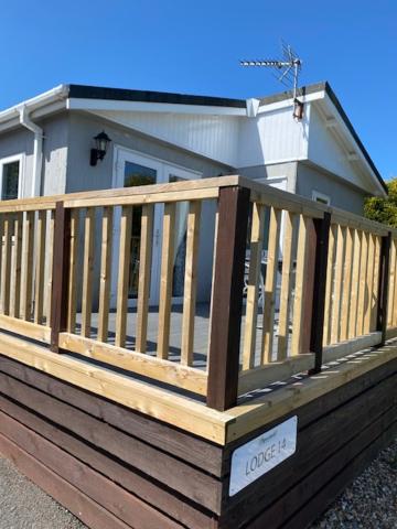 a house with a wooden deck in front of it at Lodges at Bryncarnedd, Aberystwyth in Aberystwyth
