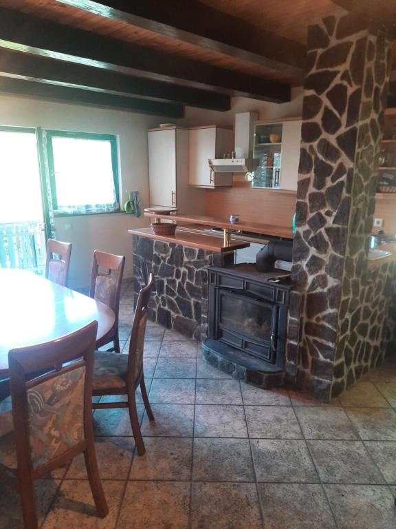 a kitchen with a stone fireplace and a table with chairs at Pocitniska hisa na Pohorju in Pohorje