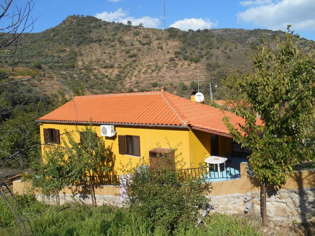 a yellow house with an orange roof in front of a mountain at Casa do Souto in Quinta do Souto