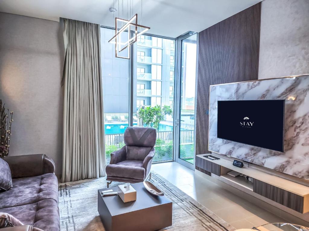 - un salon avec une grande télévision à écran plat dans l'établissement STAY BY LATINEM Luxury 1BR Holiday Home CV A207 near burj khalifa, à Dubaï