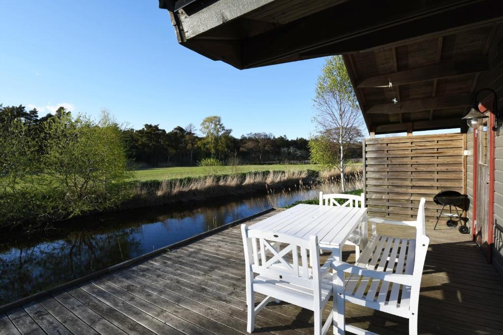 una mesa y sillas en una terraza junto a un río en Holiday home on southern Gotland en Stånga