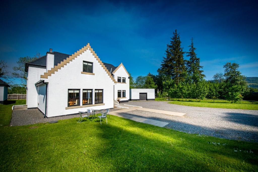 ein weißes Haus mit Stühlen auf dem Gras in der Unterkunft Achnagairn Estate - Self-catering Mini Manors in Beauly