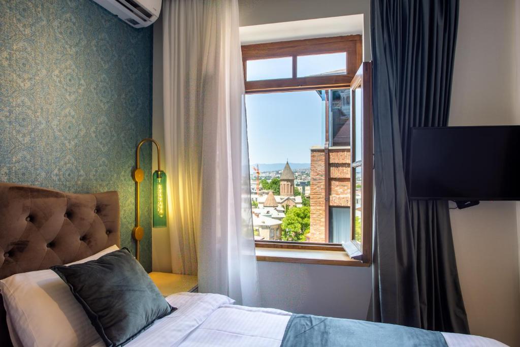 a bedroom with a bed and a window with a view at Betlemi Hotel in Tbilisi City