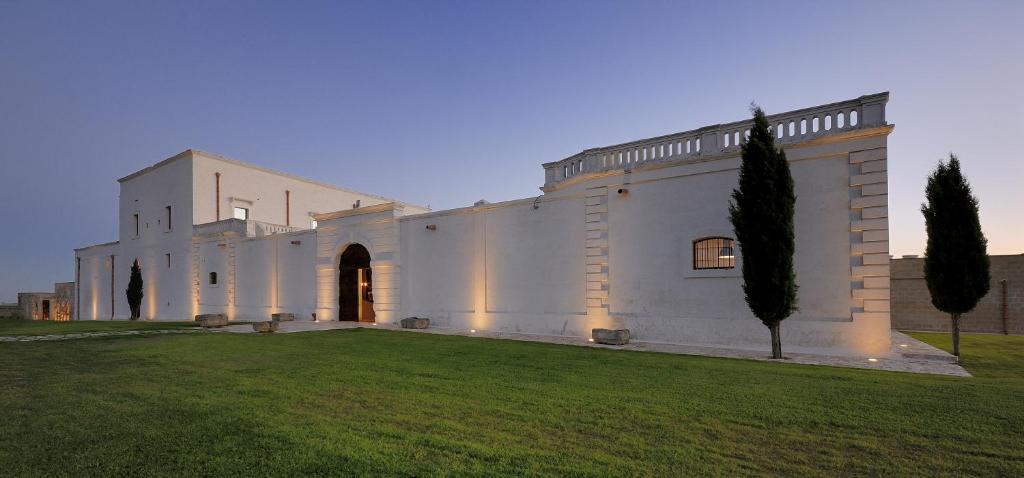 a large white building with a grass yard at Masseria Amastuola Wine Resort in Crispiano