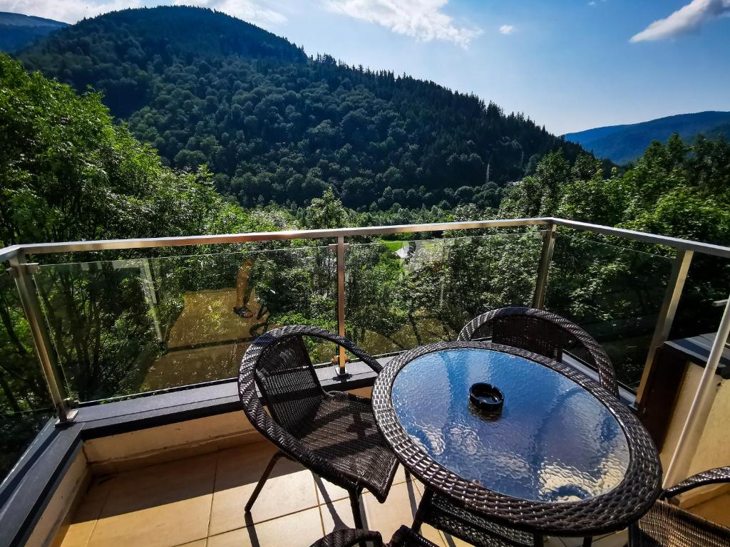 a table and chairs on a balcony with a view at Orchid Luxury Apartment Sinaia in Sinaia
