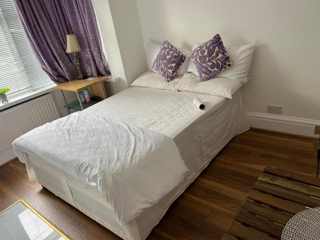 a bedroom with a white bed with purple pillows at Lovely Studio flat in London in London