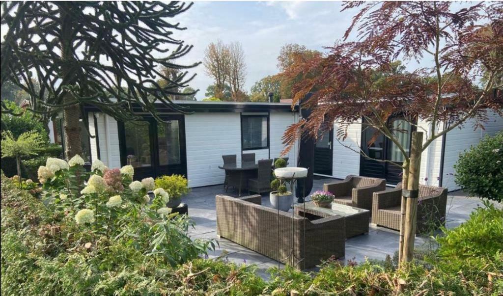 einen Garten mit einem Haus mit einer Terrasse und einem Haus in der Unterkunft Vakantiehuis “Het Zeepaard” in Voorthuizen