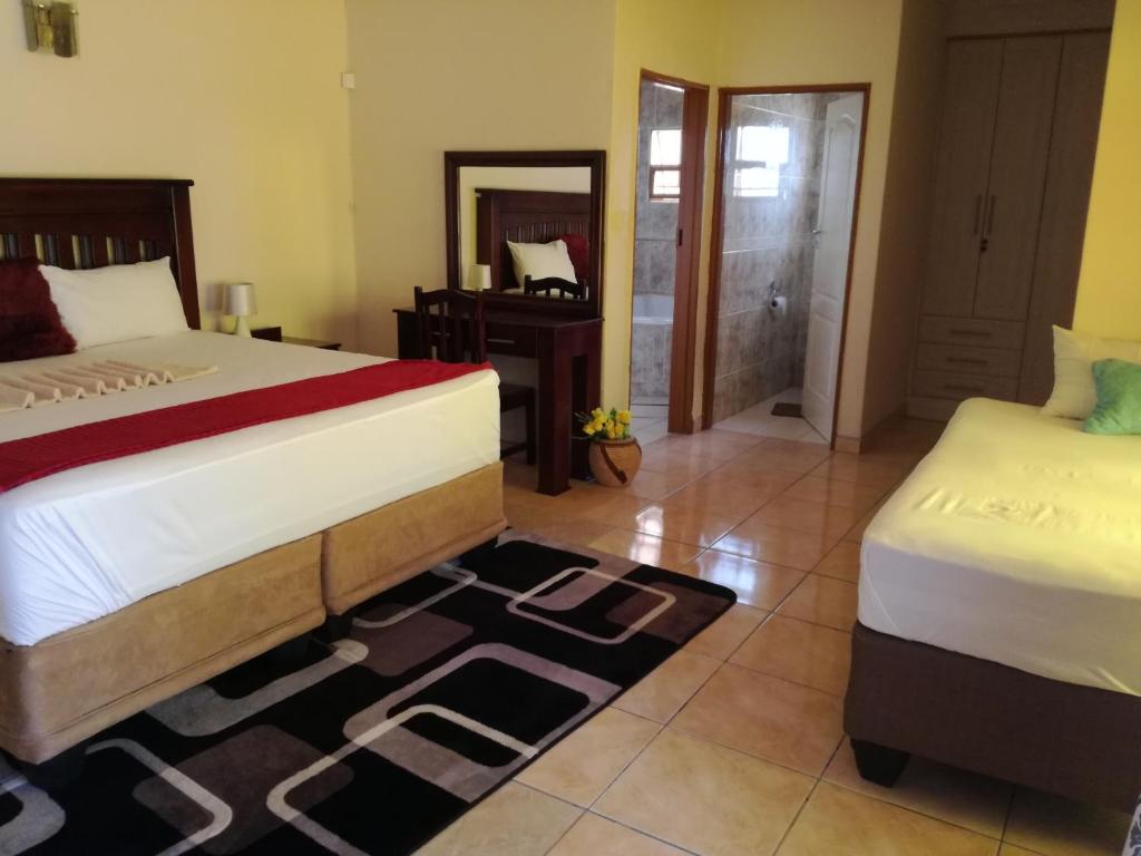 Un dormitorio con dos camas y un espejo. en DEN VIEW GUESTHOUSE, en Francistown