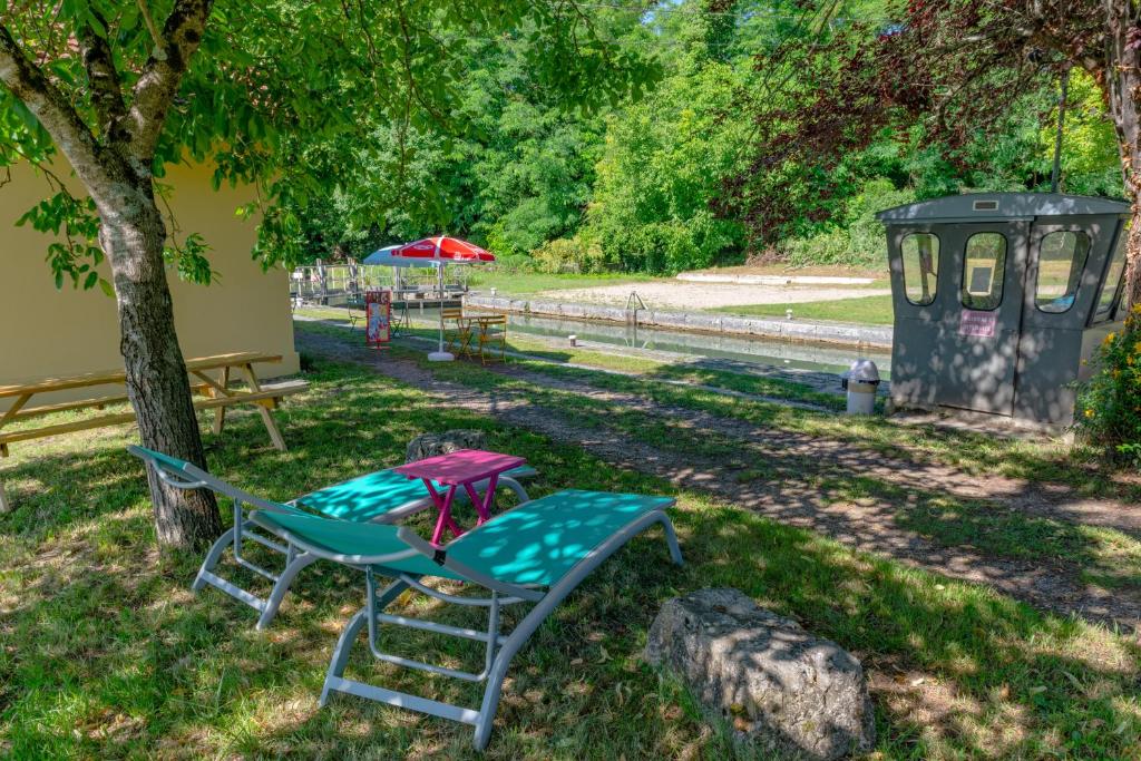 una silla y una mesa bajo un árbol en un parque en La Maison Berry, hébergement avec petit-déjeuner en Puch-dʼAgenais