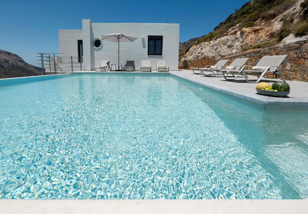 a swimming pool with chairs and a villa at Villa Aires in Vrachasi