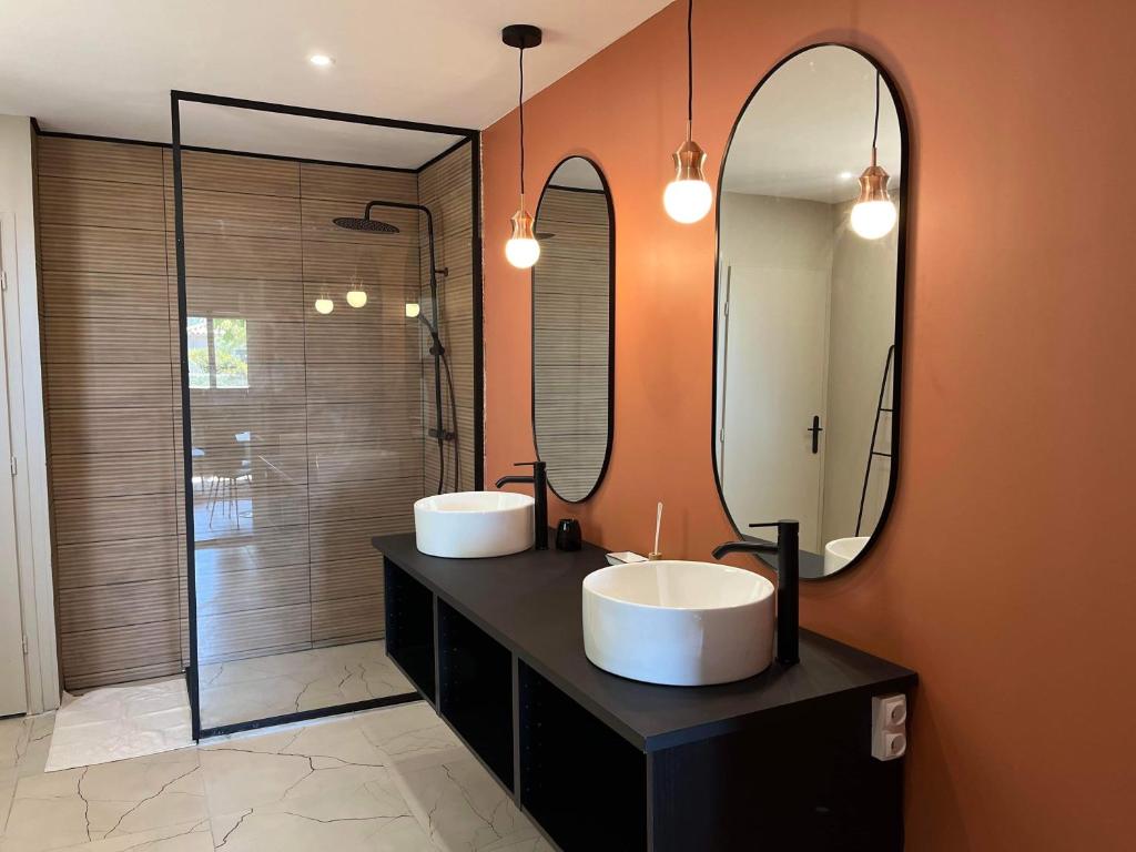 a bathroom with two sinks and two mirrors at Appartement Les Camélias proche La Rochelle in Périgny
