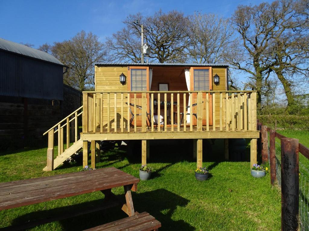 a large wooden house with a porch and a bench at The Lazy Shepherd in East Pennard