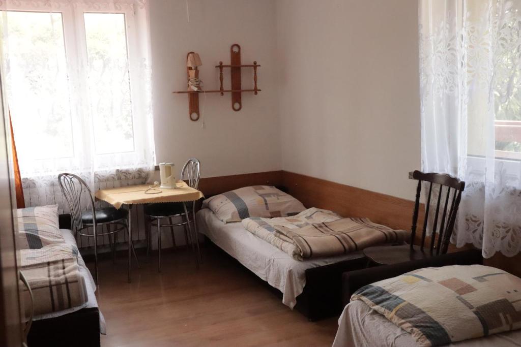 Zimmer mit 2 Betten, einem Tisch und einem Fenster in der Unterkunft Dom Wczasowy Pod Weską in Korbielów