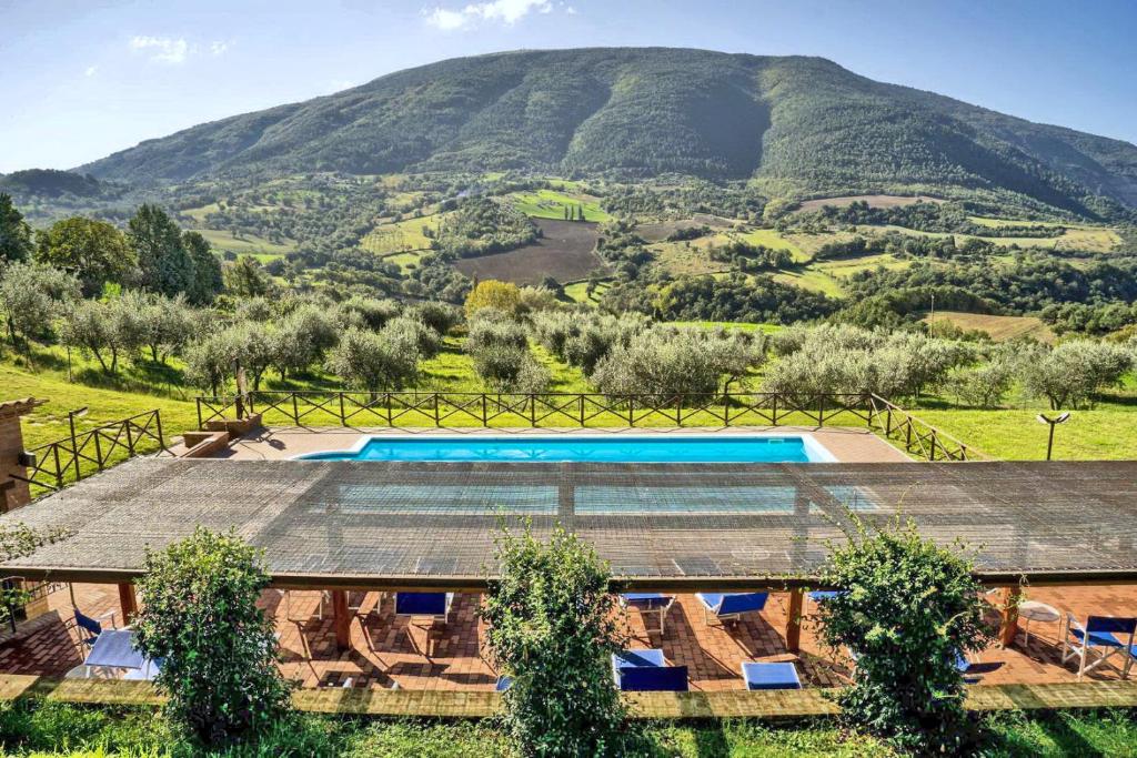 a villa with a swimming pool and a mountain in the background at Villamena in Assisi