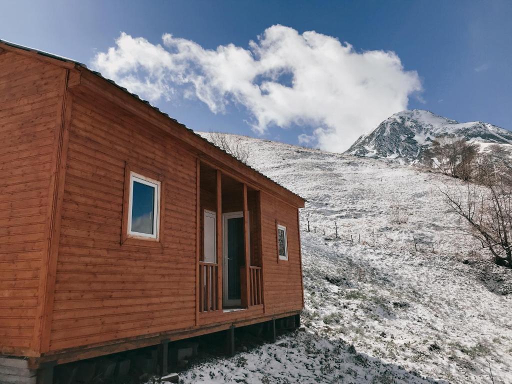 a wooden house on a snowy hill with a mountain at amo-isuntke in Jut'a