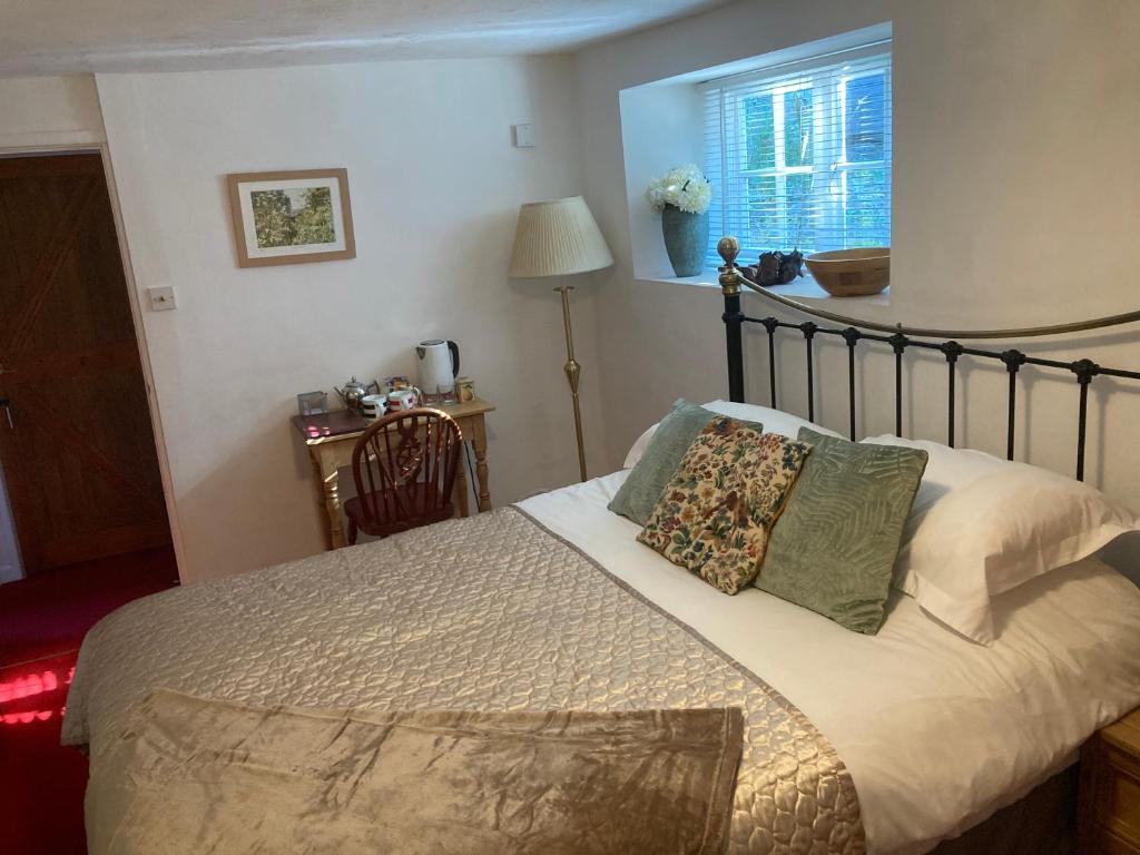 ein Schlafzimmer mit einem Bett mit Kissen und einem Fenster in der Unterkunft Bissick Old Mill Suite in Truro